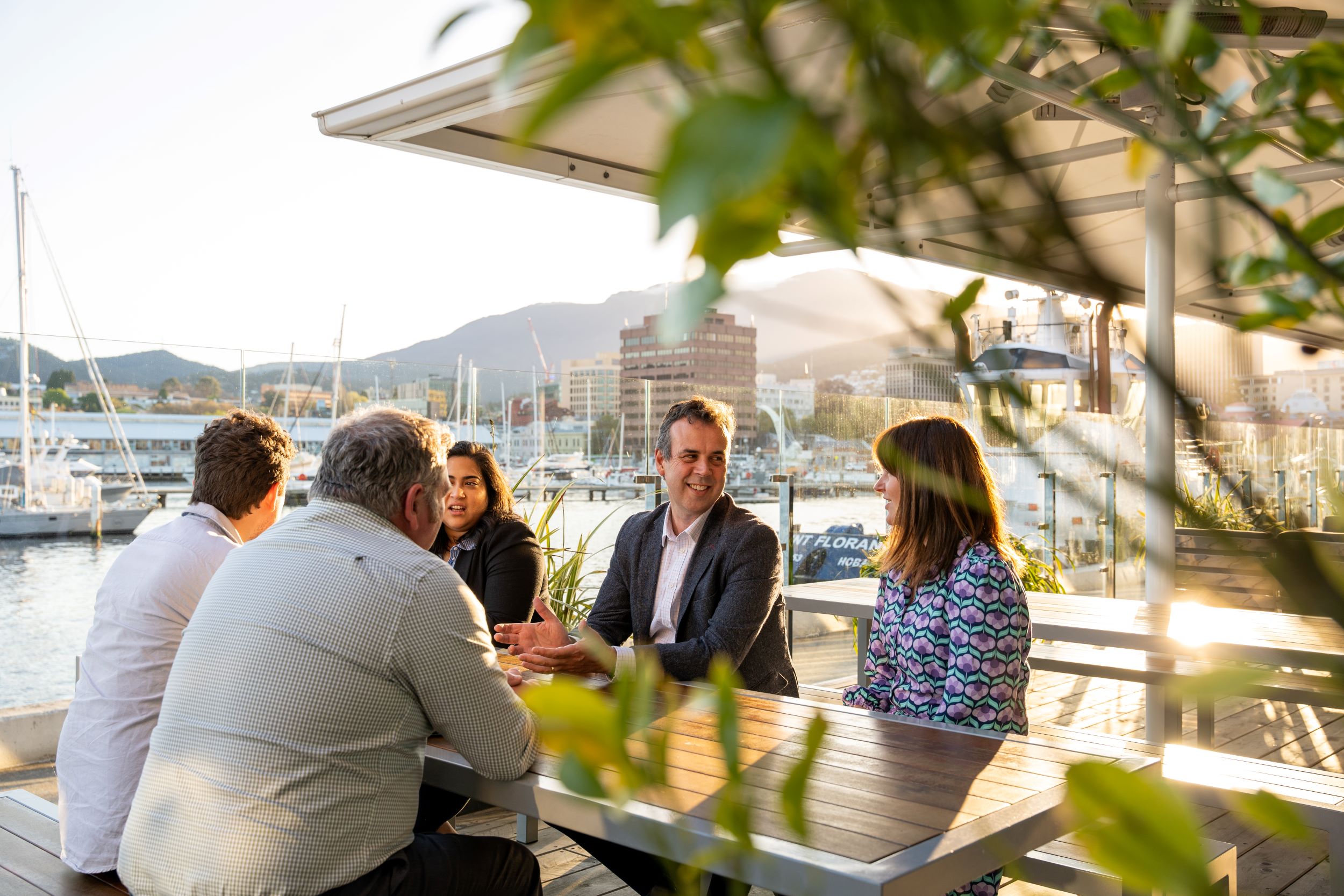 2PM staff sitting at a table, with Hobart and Mount Wellington in the background